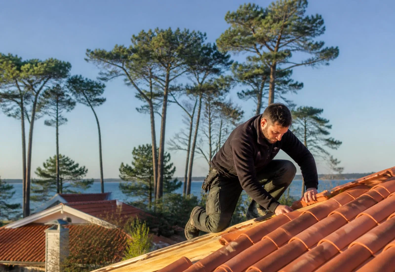Couvreur posant des tuiles canal sur une toiture à La Teste-de-Buch, pins maritimes du Bassin d'Arcachon